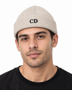 CD Fisherman Beanie — Natural, worn front portrait on a white background with black CD embroidery.