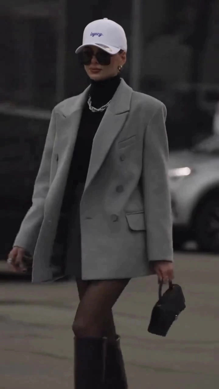 White Augusta Legacy cap worn with a grey blazer on a city street