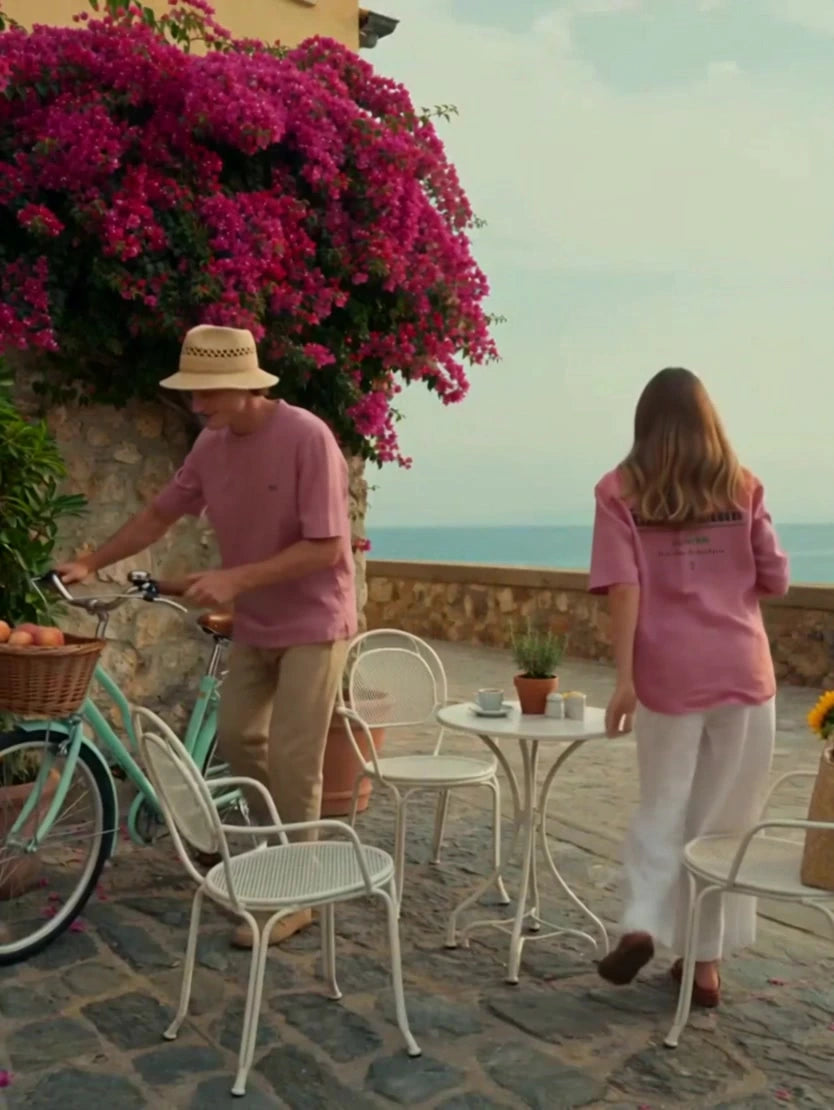 Two people wearing pink Augusta People’s Club T-shirts, with the back print visible on one