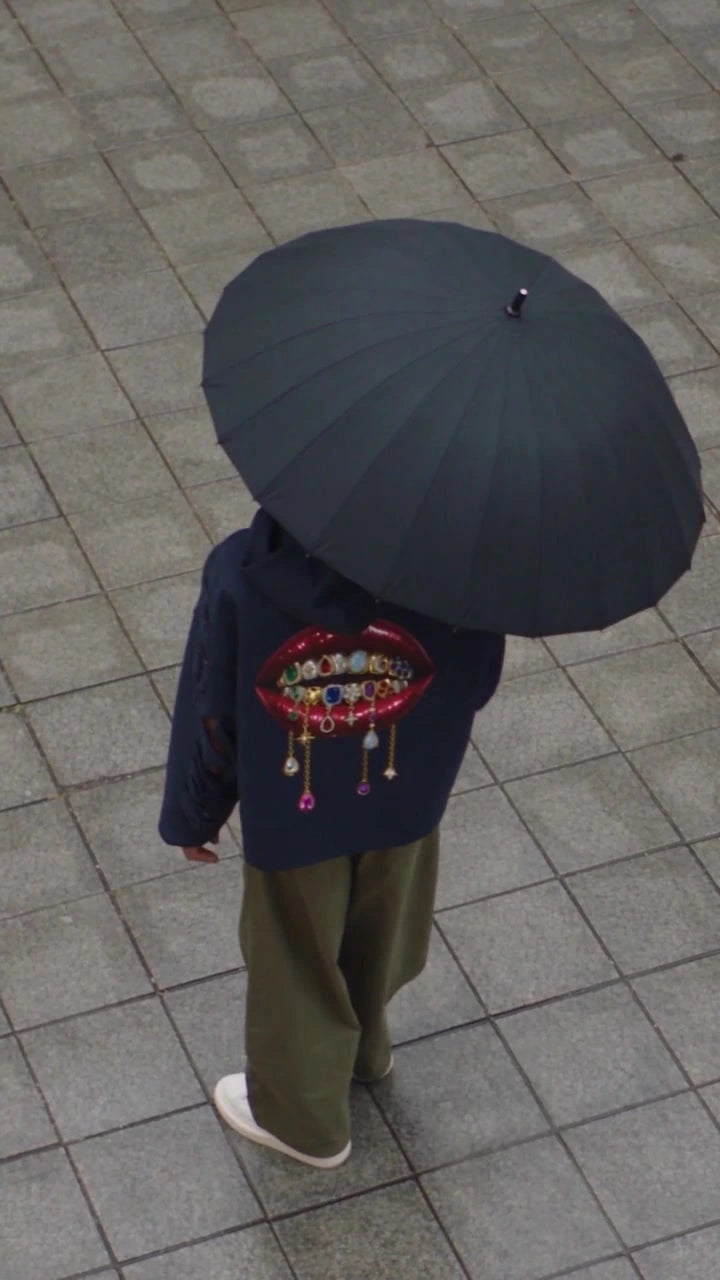 Back of an Augusta Rare Form navy hoodie with the mouth and pendants graphic under an umbrella