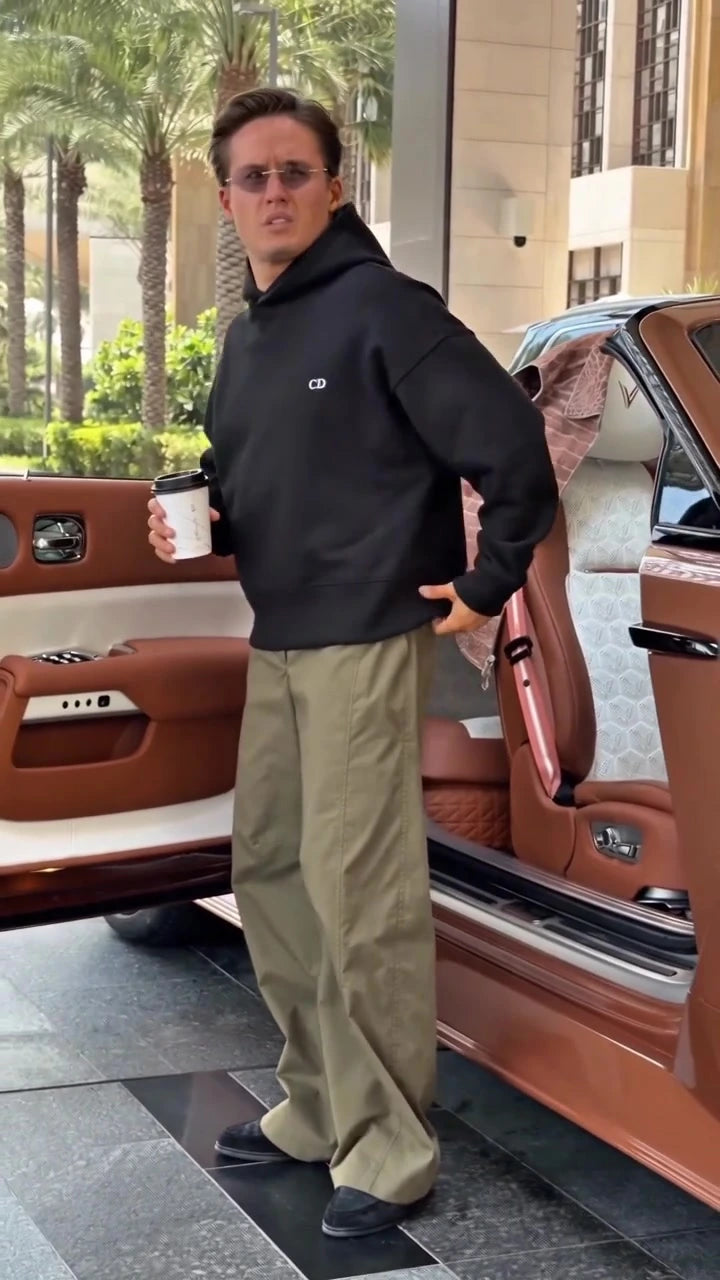 Front view of a black Augusta Soft Power hoodie beside a parked car